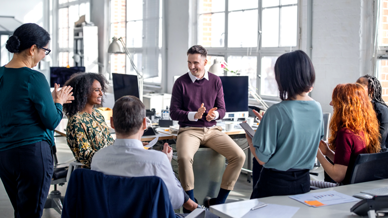 Group of business people clapping hands for a coworker in staff meeting