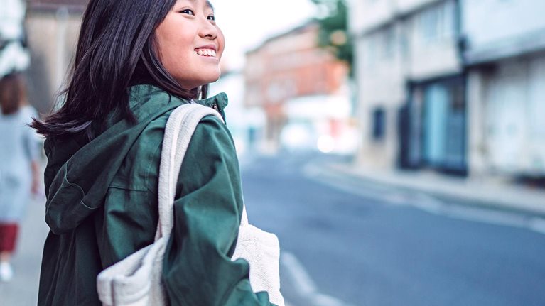 Cheerful teenage girl walking in the street while exploring in a town