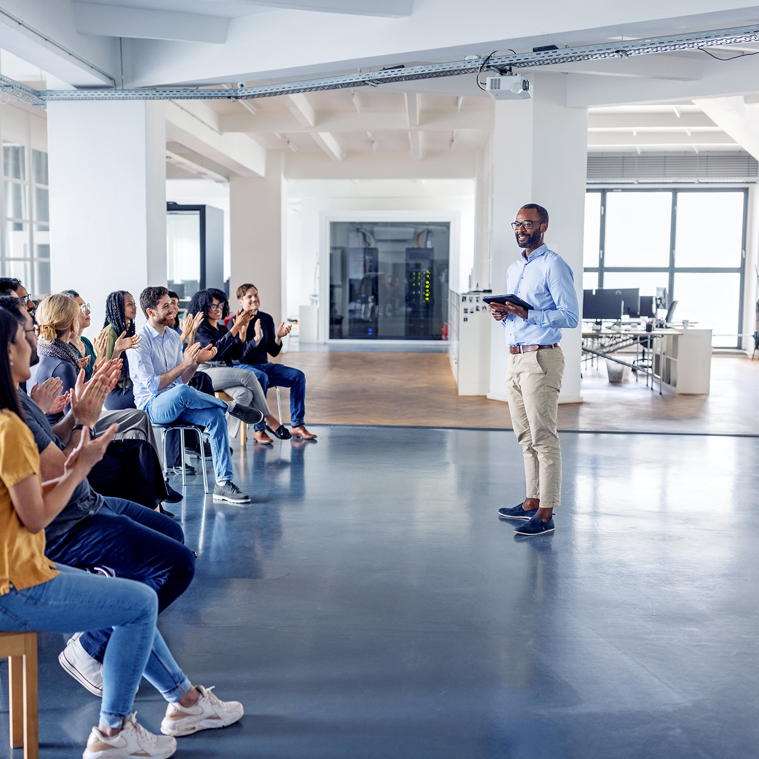 An image of a business team clapping and celebrating at a team-building session in a modern office.