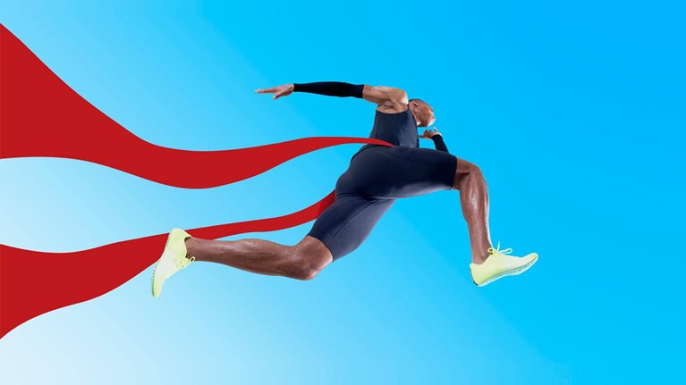 An Olympic runner crossing the finish line, the red ribbon fluttering behind him.