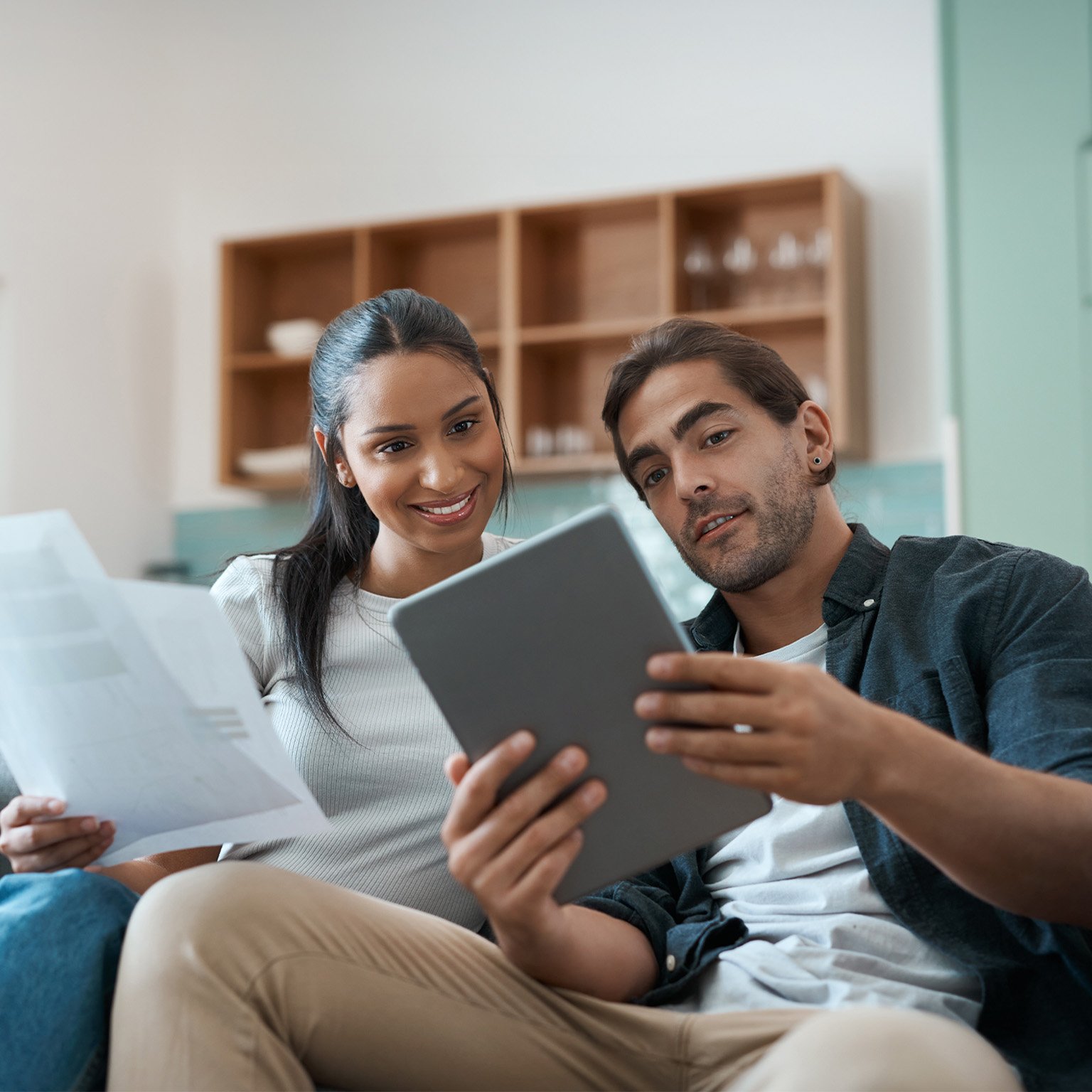 Shot of a young couple doing paperwork while using a digital tablet at home