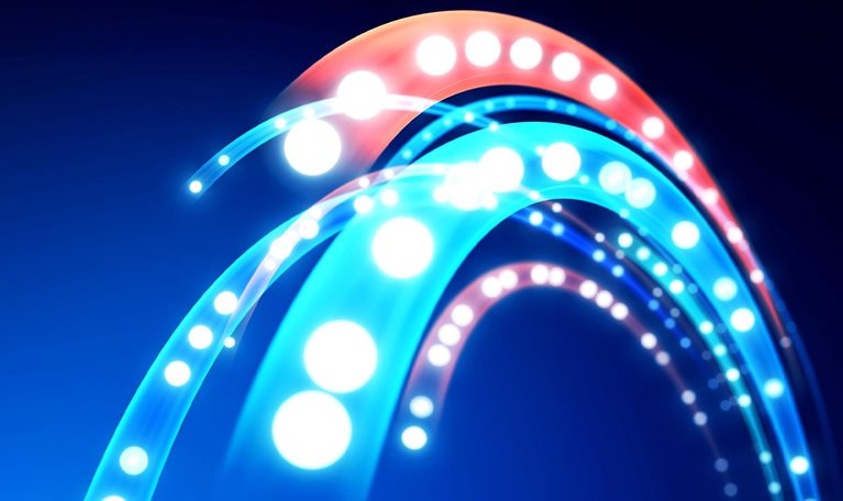 An abstract close-up of glowing curved light trails in bright cyan, blue, white, and coral against a dark background.