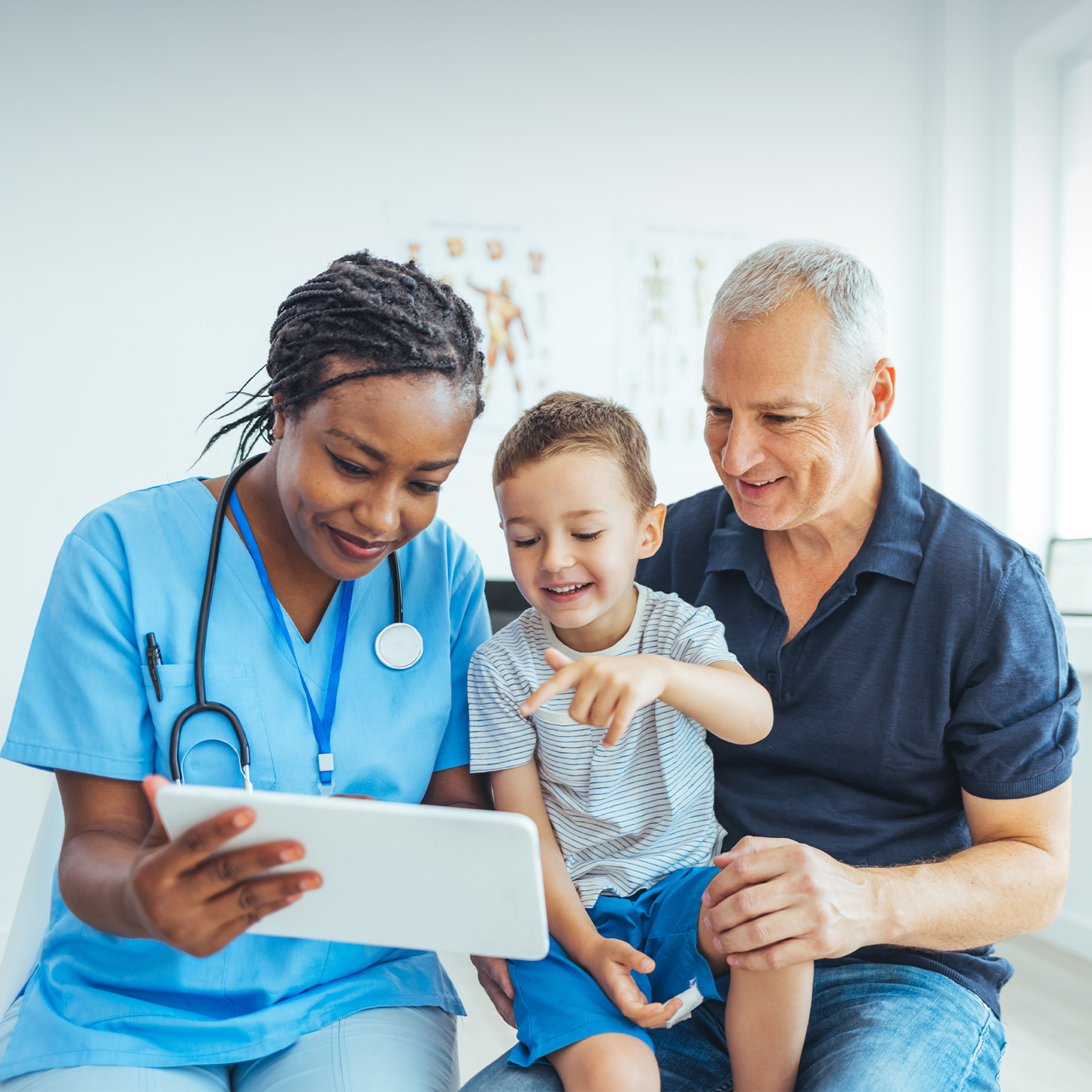 Female pediatrician doctor showing father medical results on tablet in clinic.