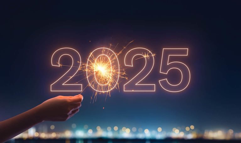 Hand holding sparkler behind 2025 sign