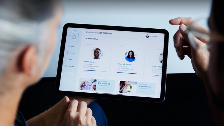 Two doctors looking at patient data on digital tablet - stock photo
