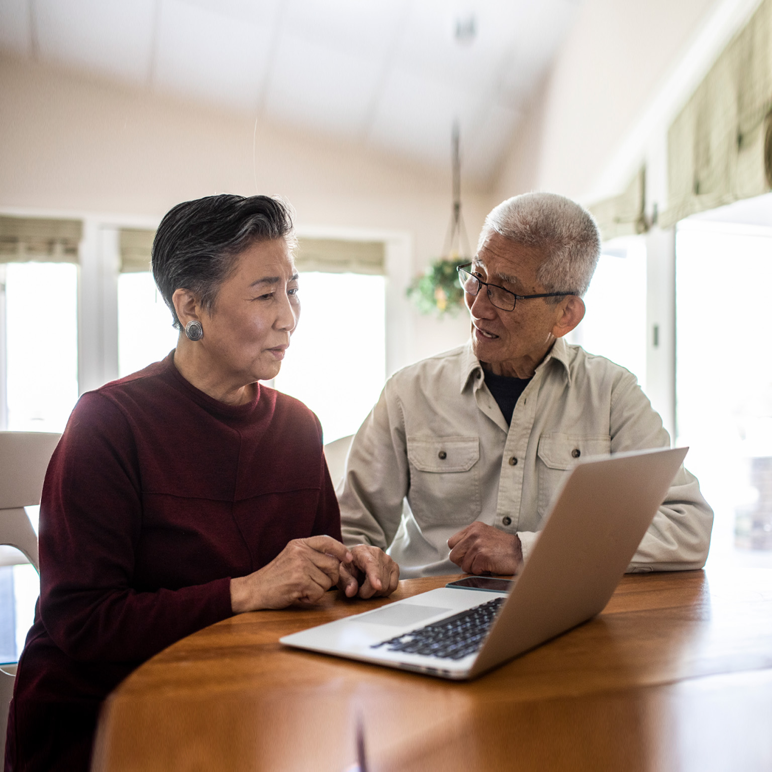 elderly couple talking in front of open laptop