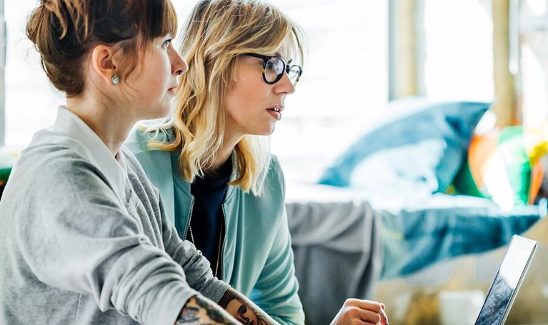 Two businesswomen working on a computer - stock photo