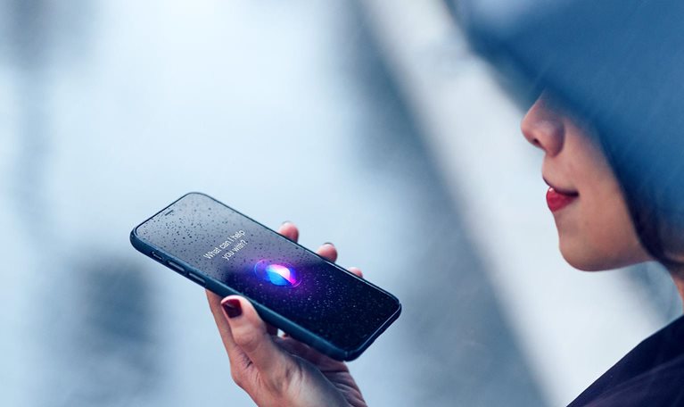 Image of a woman using voice assistant on smartphone in the rain.