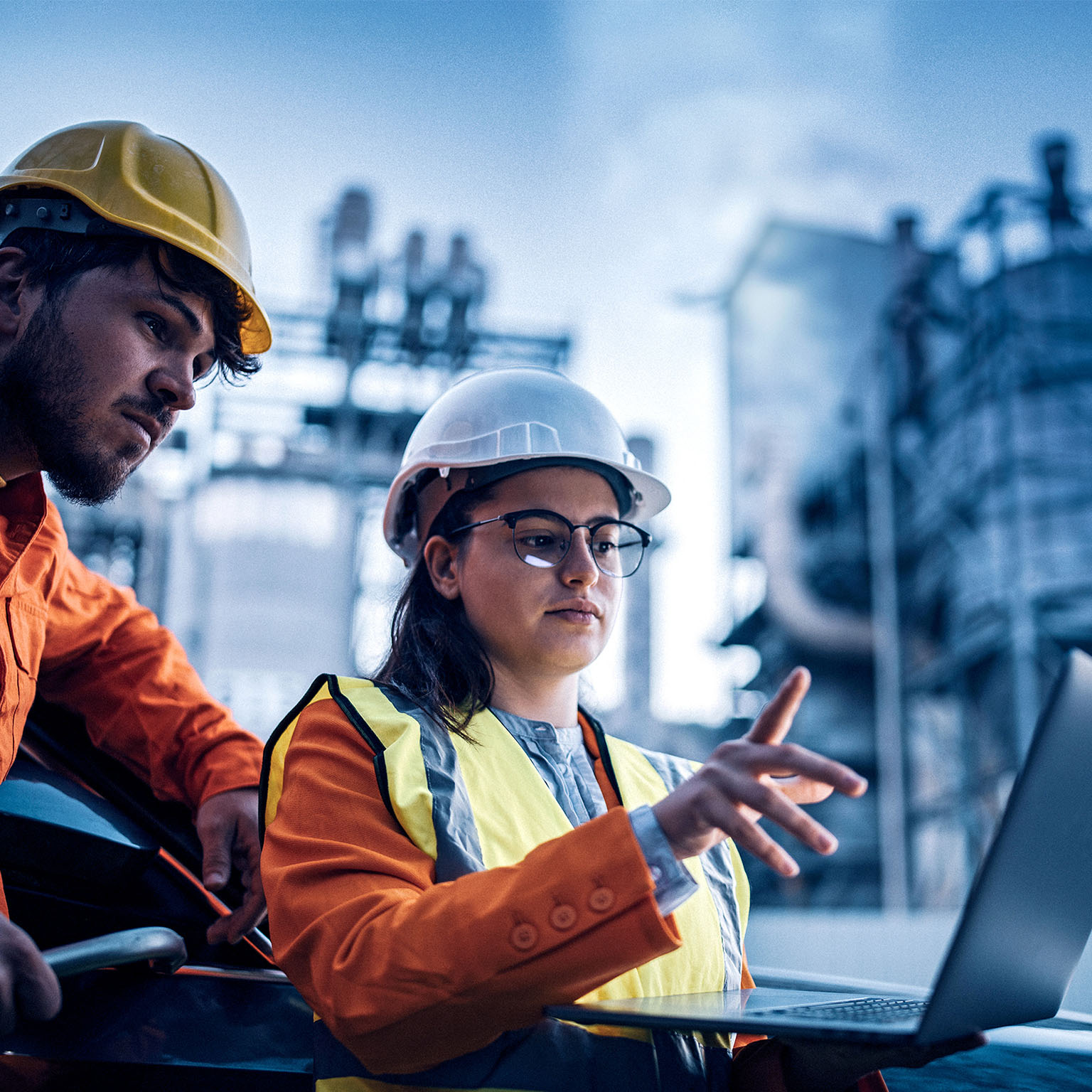  Two engineers, man and woman, using laptop to work at power plant on night shift