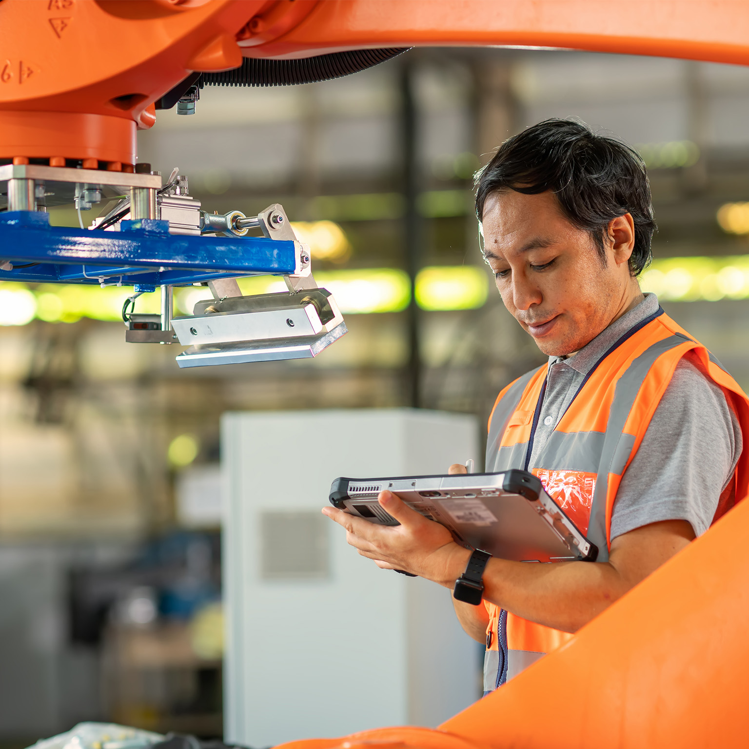 Male Japanese Engineer inspecting the Robotic working synchronize with conveyor of ingot production line by compare data with computer tablet during installation in factory.