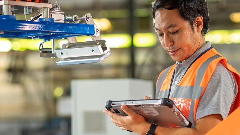 Male Japanese Engineer inspecting the Robotic working synchronize with conveyor of ingot production line by compare data with computer tablet during installation in factory.
