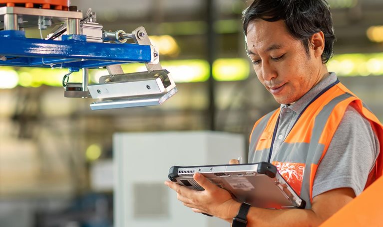 Male Japanese Engineer inspecting the Robotic working synchronize with conveyor of ingot production line by compare data with computer tablet during installation in factory.