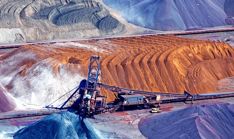 An aerial image of a piles of ore organized around a conveyor belt.