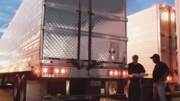 Two truck drivers standing next to truck trailers