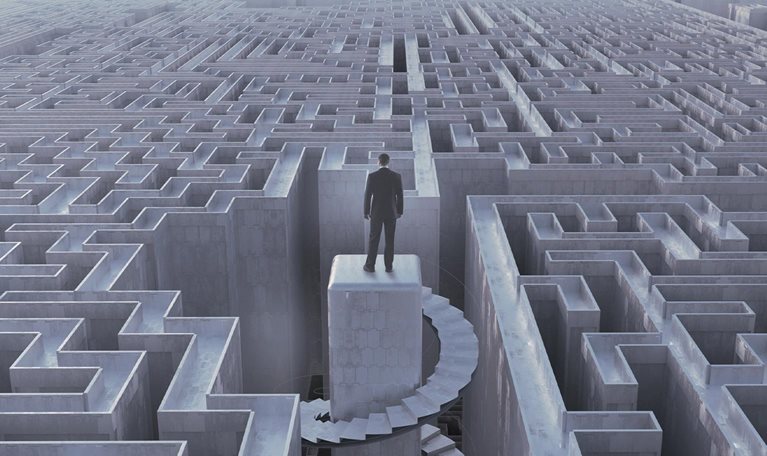 Businessman stranded at top of complex maze - stock photo