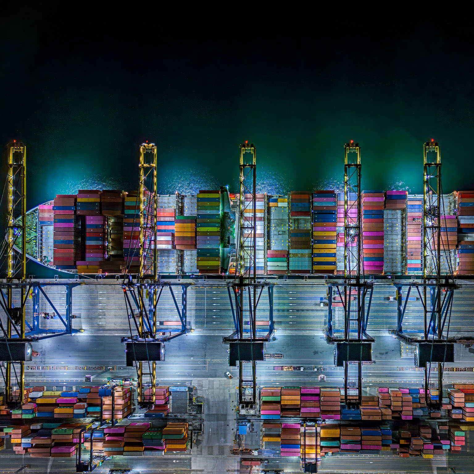 Aerial top view of container ships at dock during twilight. - stock photo