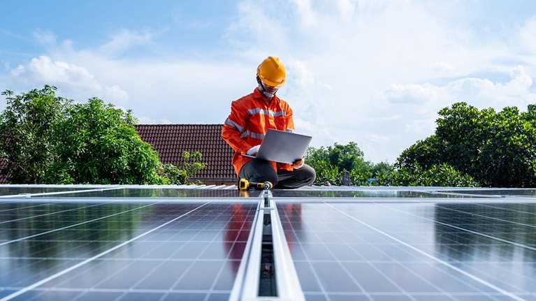 Technicians man working with laptop at solar power station on the roof, Solar energy technology concept - stock photo