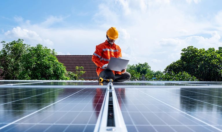Technicians man working with laptop at solar power station on the roof, Solar energy technology concept - stock photo
