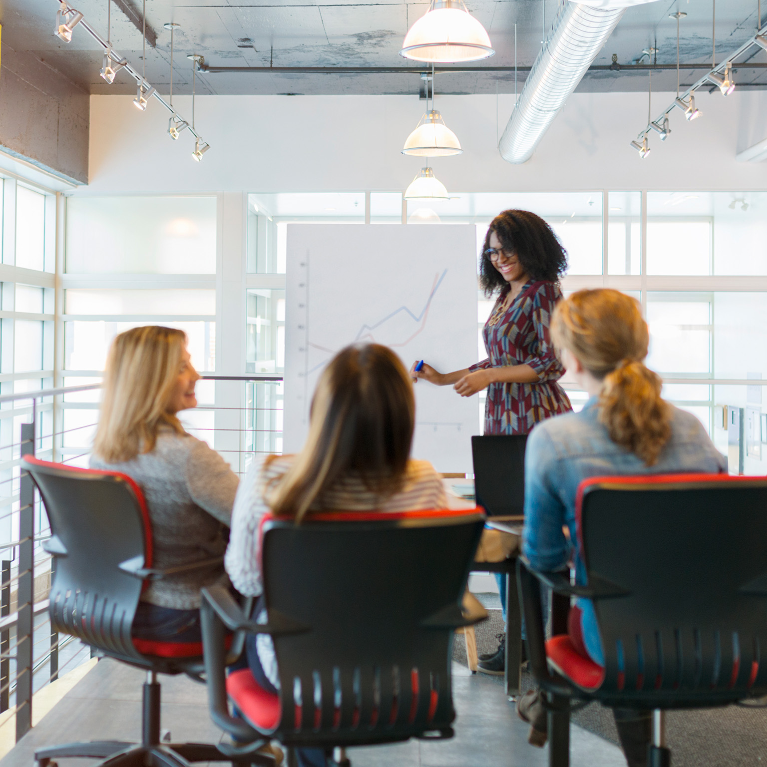 Businesswoman leading meeting at flip chart in conference room - stock photo