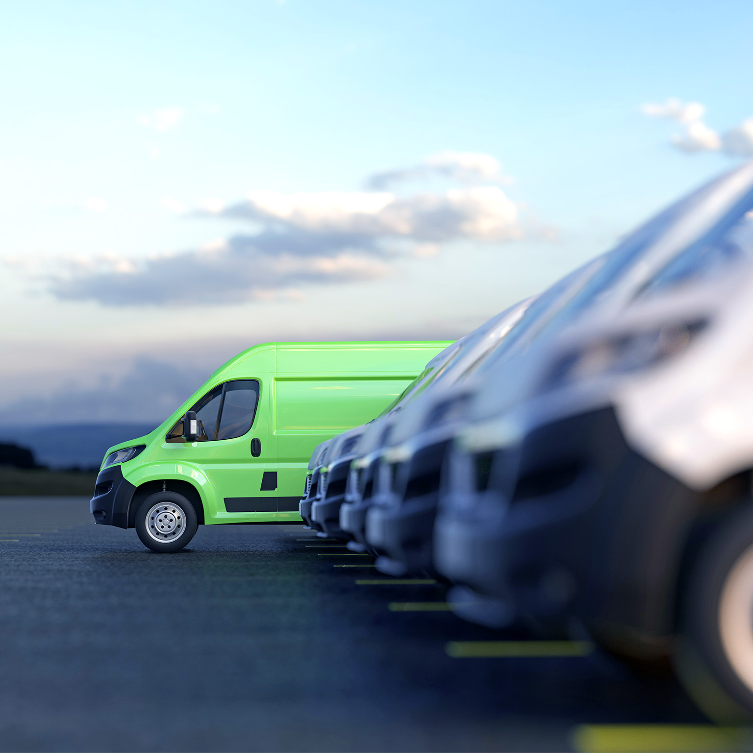 Image of a modern green electric van standing out from a row of other plain white vans.