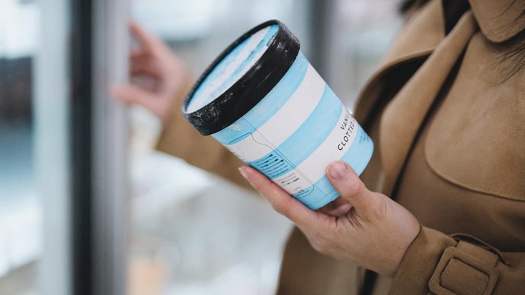 Woman holding a cup of vanilla ice cream in supermarket