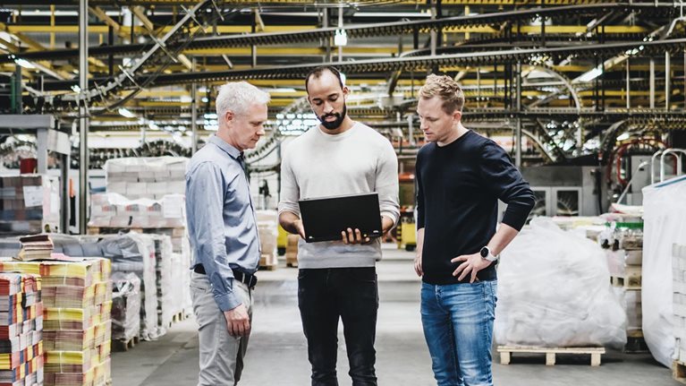 Three senior engineers using computer in warehouse