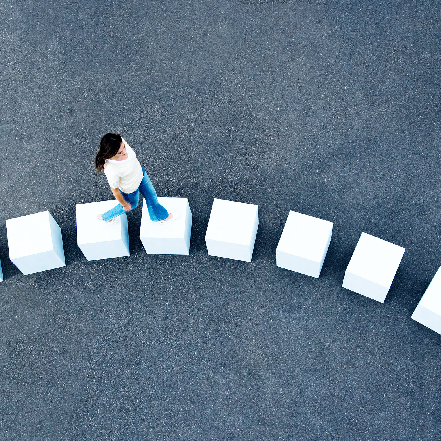 An aerial view of a woman walking across line of giant white cube