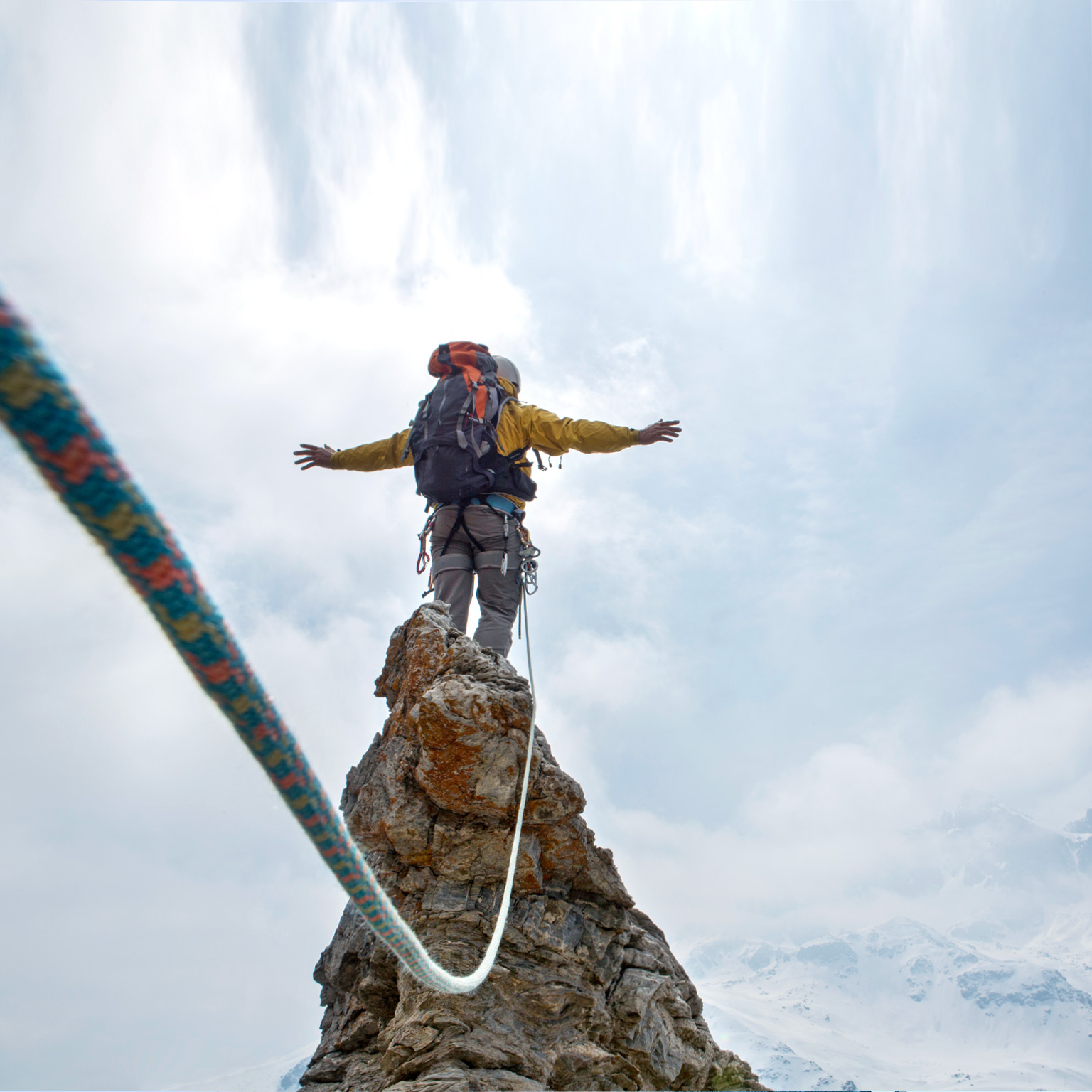 Mountaineer standing on a peak, wearing a harness