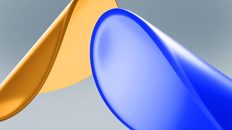 Two smooth, glossy disk-like shapes set against a soft gray background: one golden and the other blue. The lighting and reflective surfaces give the composition a sleek appearance.