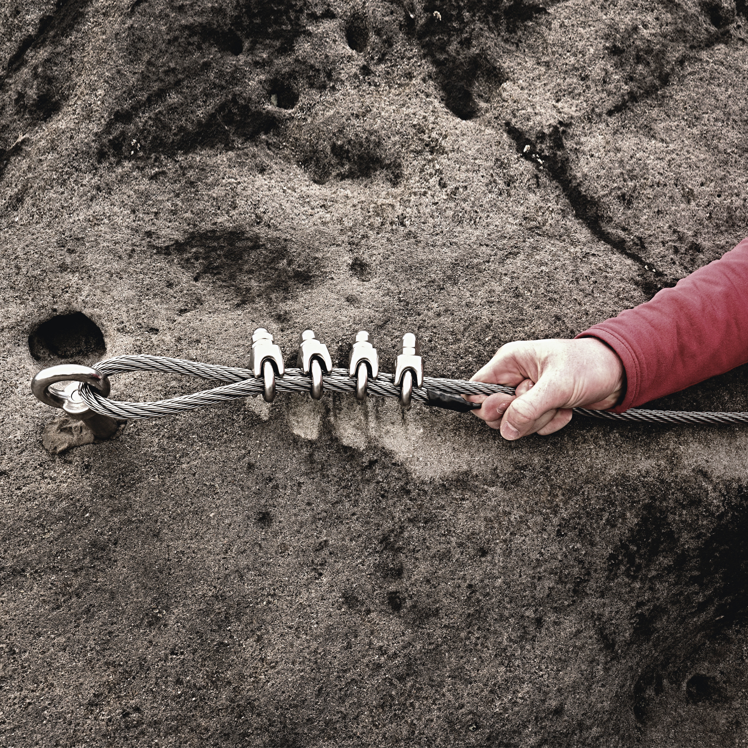 Rock climber holding on to steel twisted rope