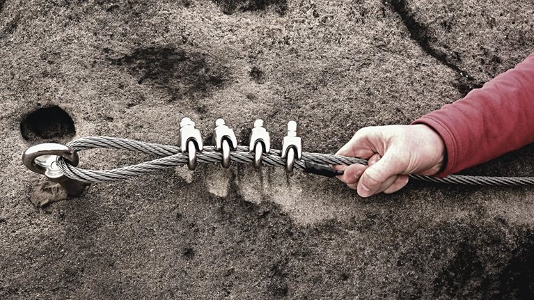 Rock climber holding on to steel twisted rope
