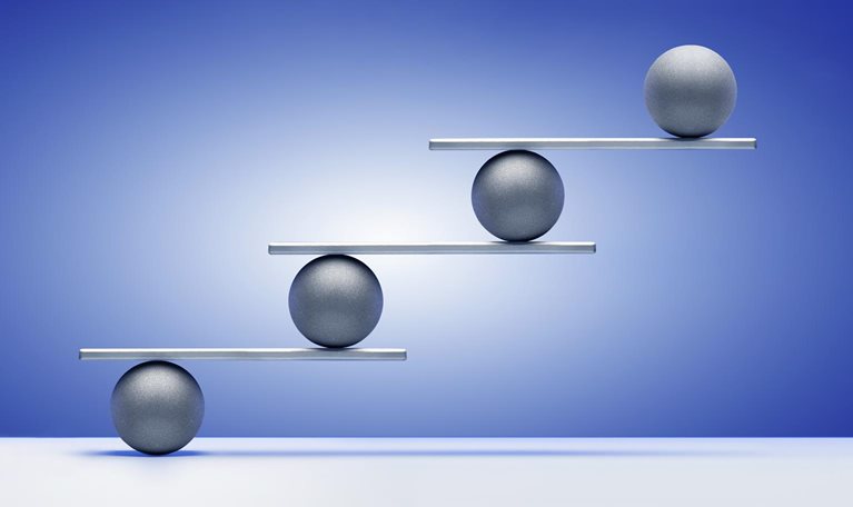 Silver colored balls on ascending white shelves, gradated blue background