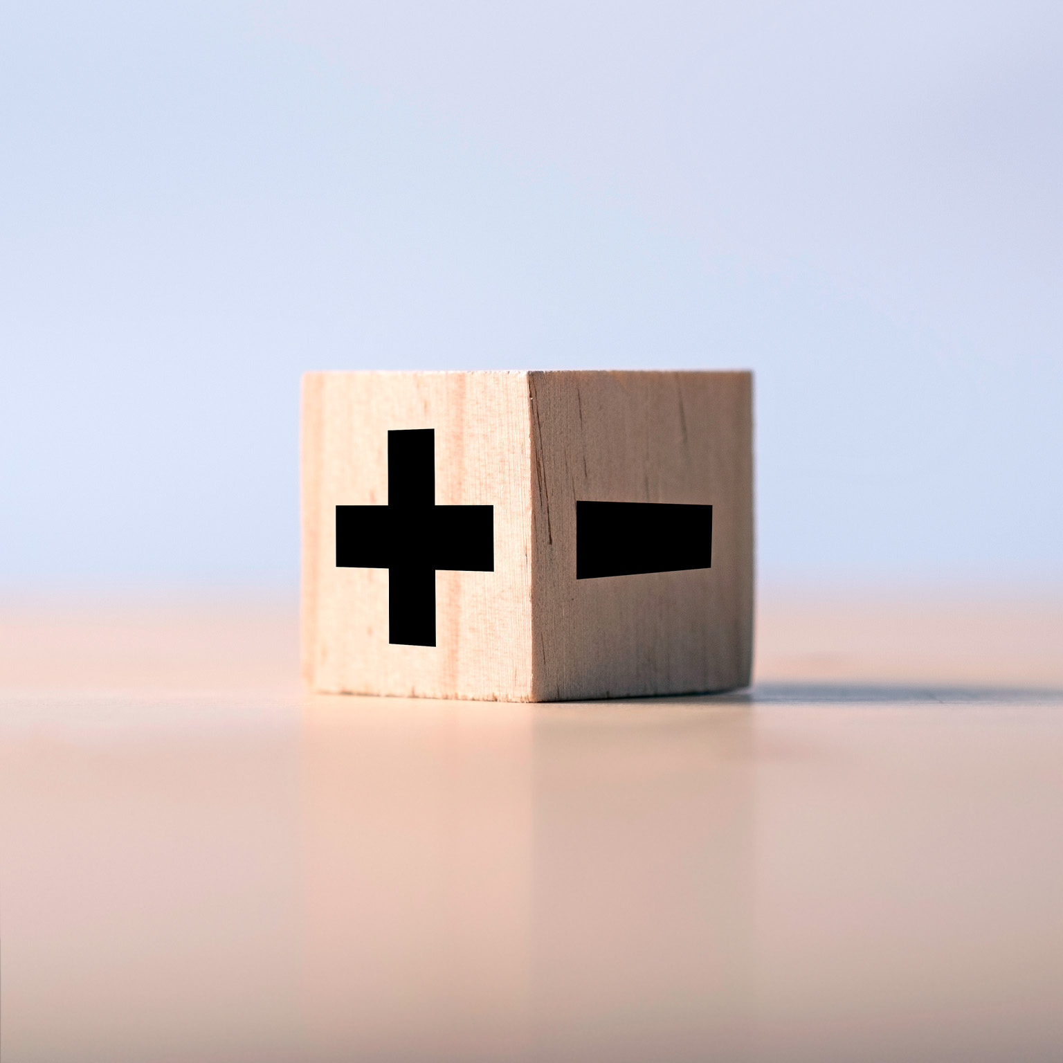 A wooden block marked with a positive and negative sign