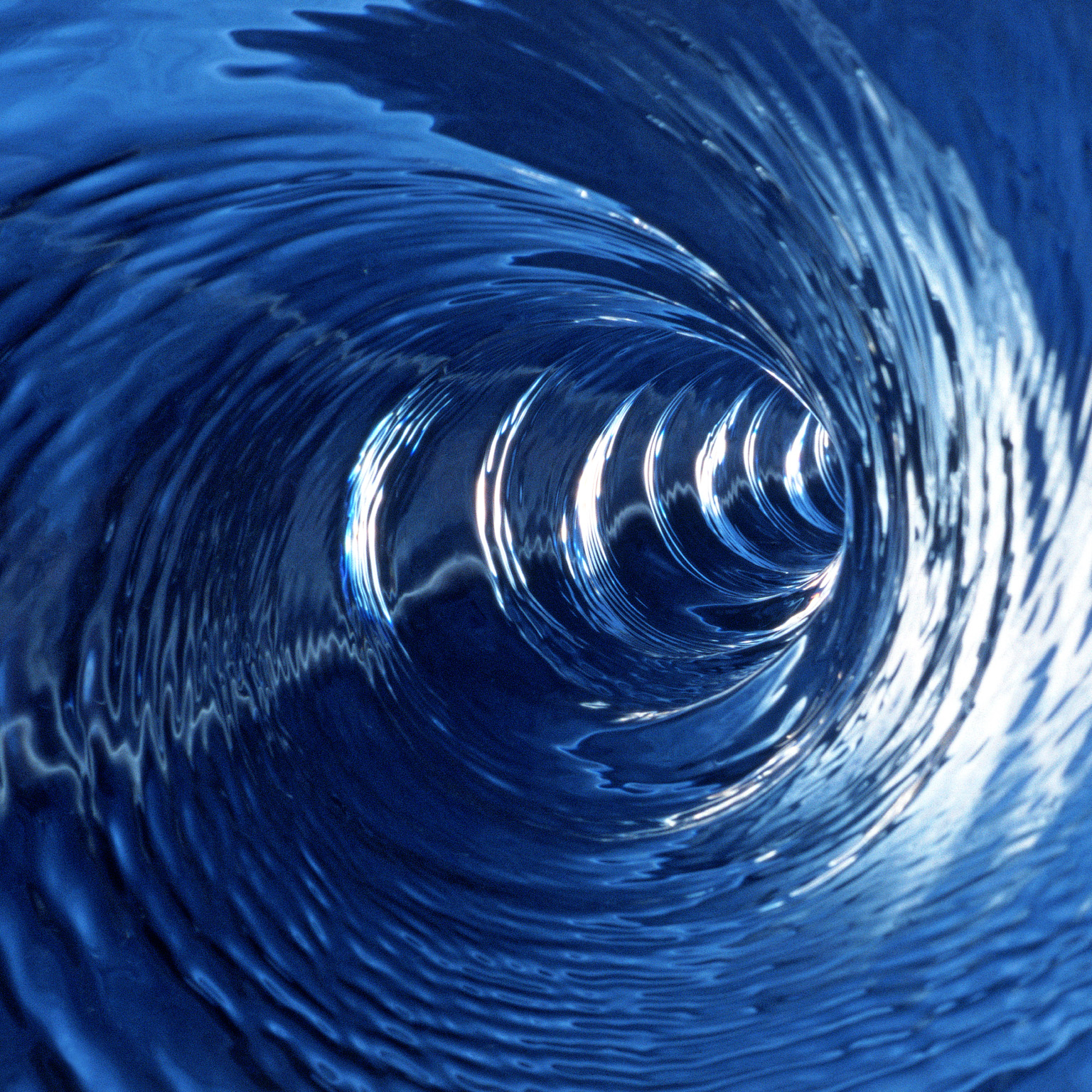 Swirling blue waters being drawn in at great speed making a conical whirlpool shape
