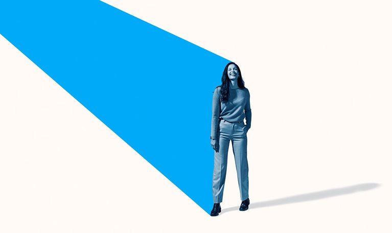 Full length image of a smiling woman standing with an angled turquoise beam