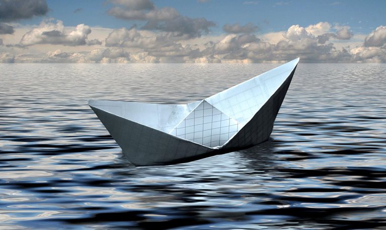 A small boat crafted from graph paper floats gracefully in the ocean, poised for an epic voyage.