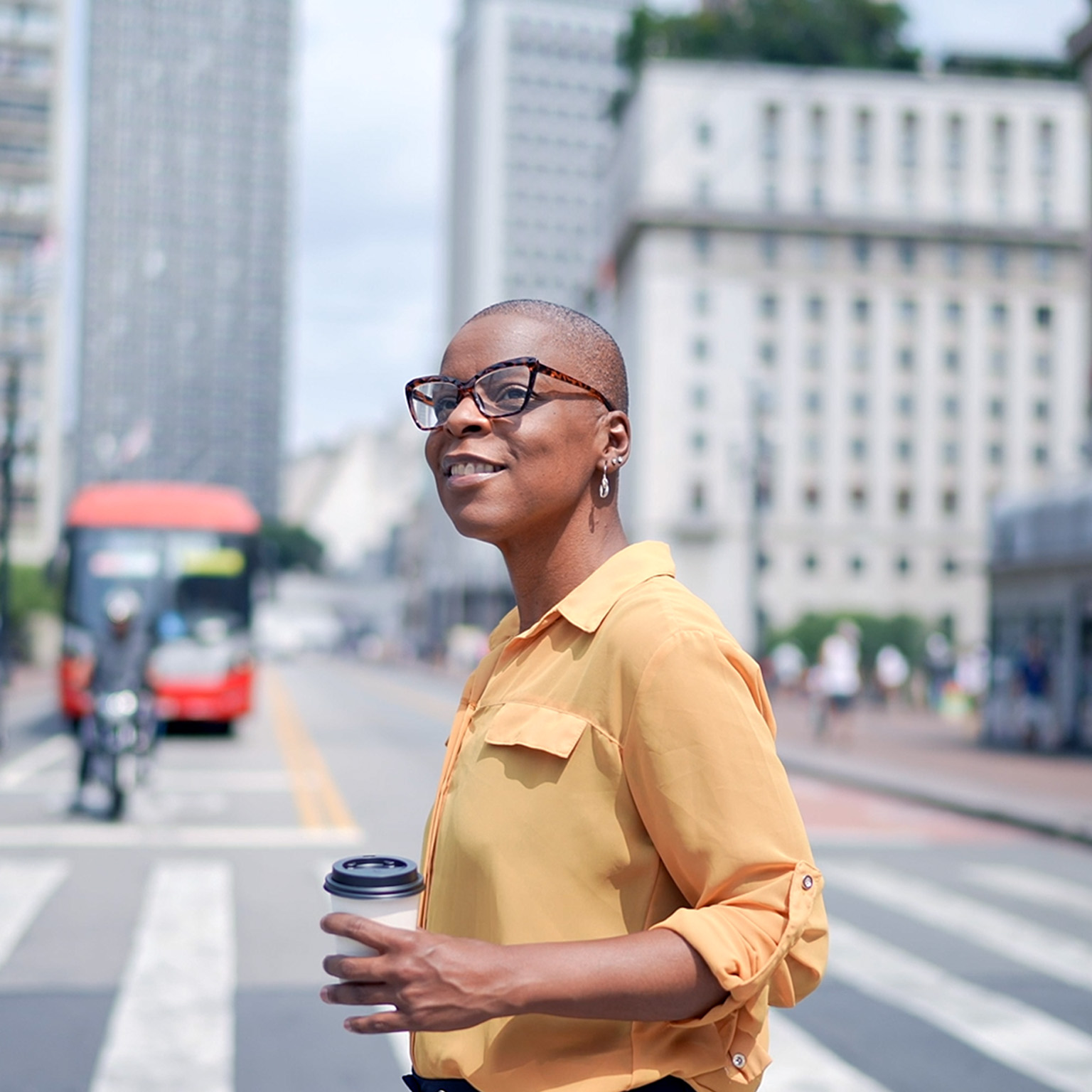 A person crossing the street holding a coffee cup