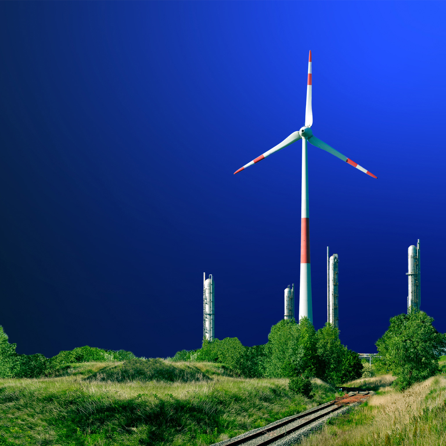 Wind turbine in front of a petrochemical installation