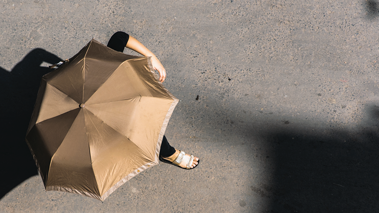 Woman using umbrella as shade from the sun
