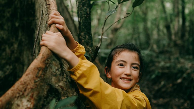 Young girl with buttress roots in a jungle in Okinawa, Japan
