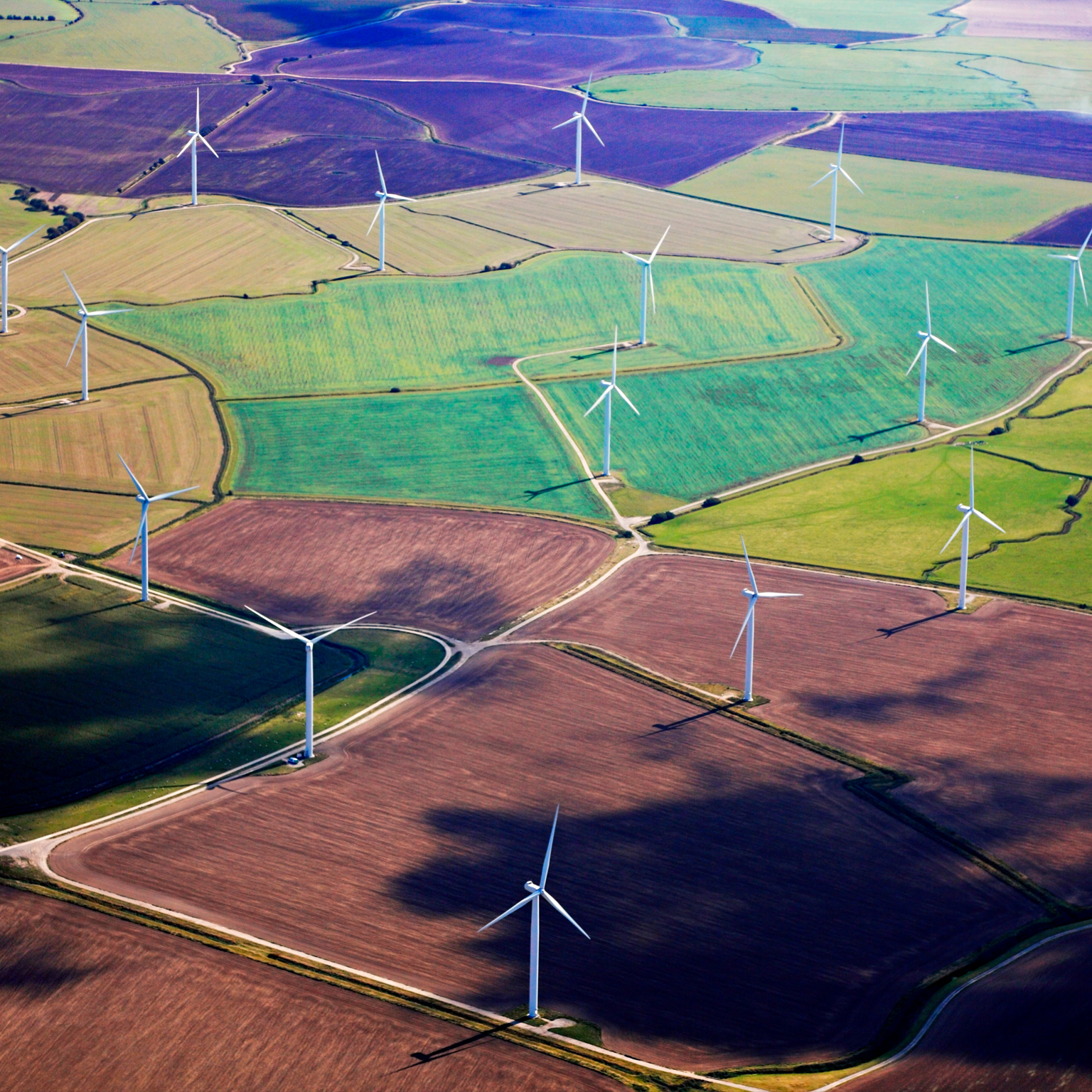 Wind Turbines amidst some colorful fields in Kent viewed from air. - stock photo