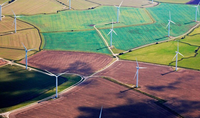 Wind Turbines amidst some colorful fields in Kent viewed from air. - stock photo