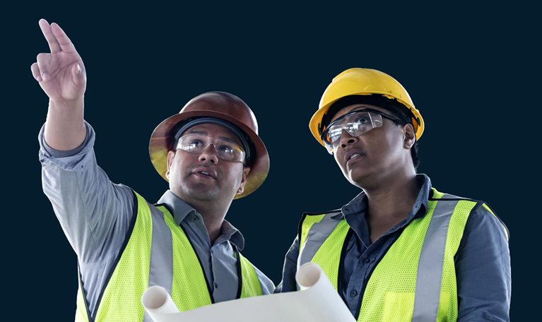 Image of a Latino man and woman construction workers looking and pointing up and away while discussion floor plans.