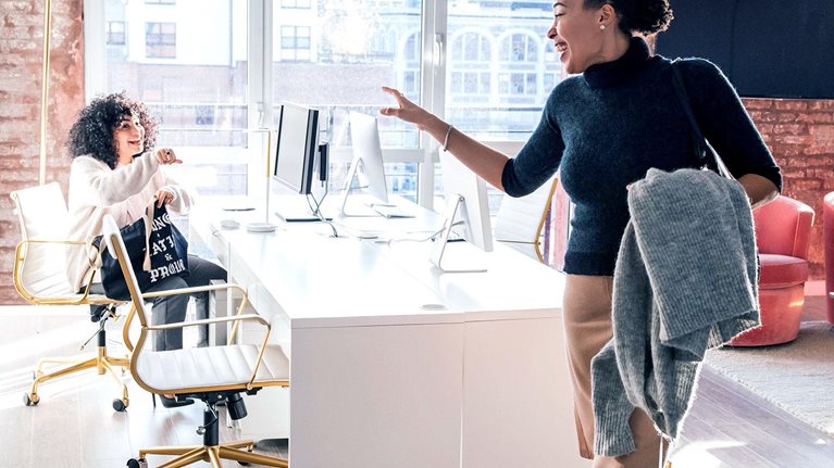 Woman waving goodbye to colleague in office