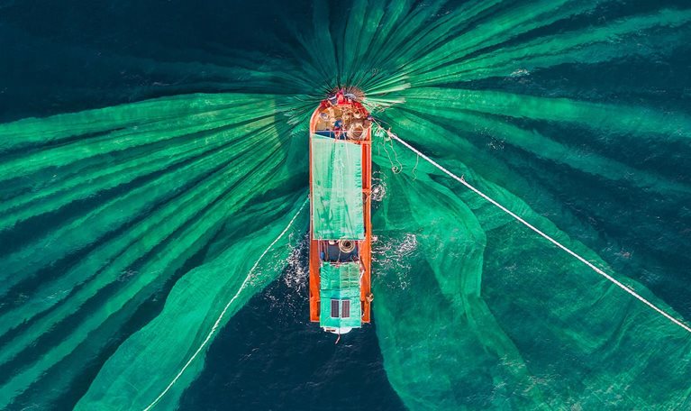 Drone photograph looking down on a fishing trawler catching anchovies, Vietnam