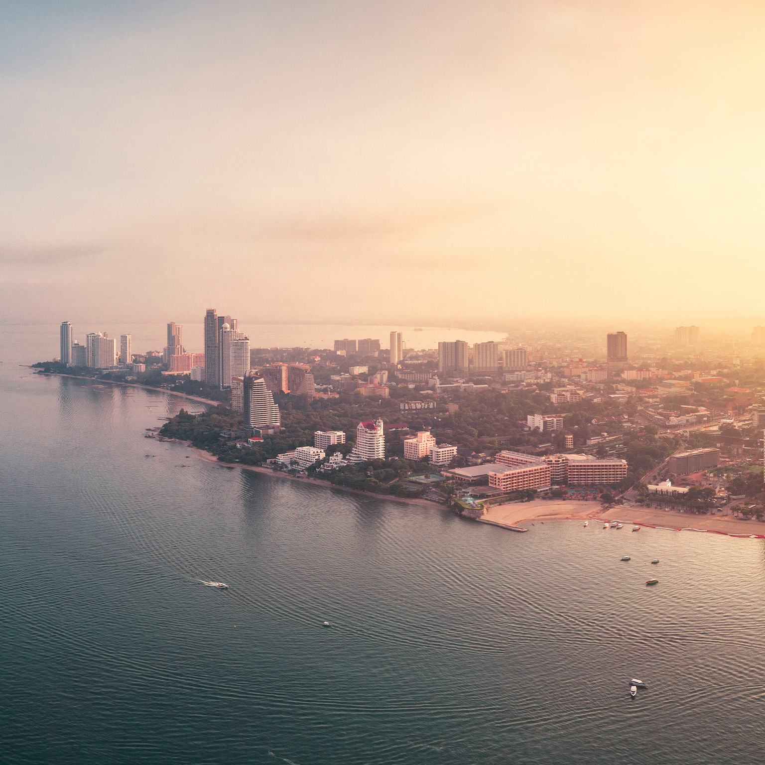Dramatic drone panoramic photo with sunrise cityscape view of the Pattaya City, Thailand and the ocean around it. - stock photo
