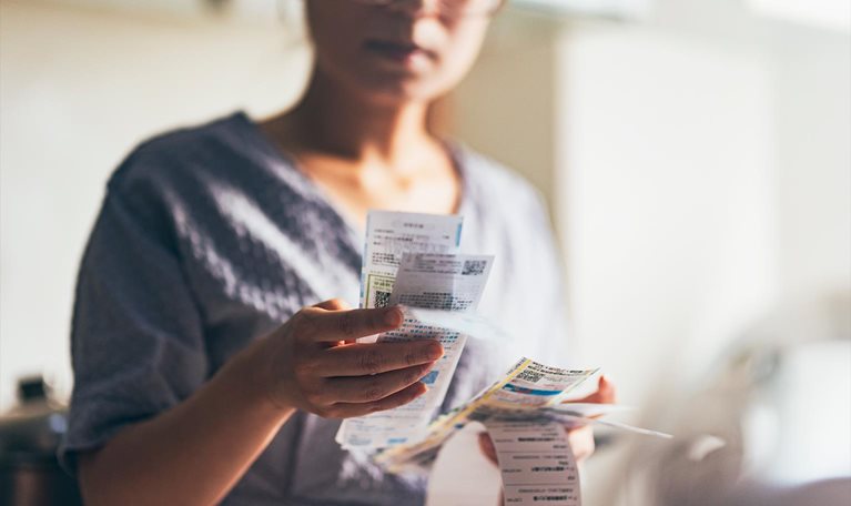 Asian women examining the shopping receipt at home - stock photo