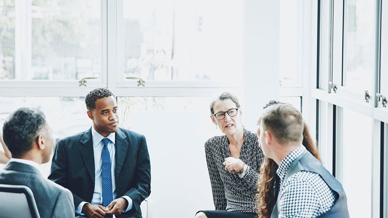 Overview of a group of C-Suite business leaders having a discussion.