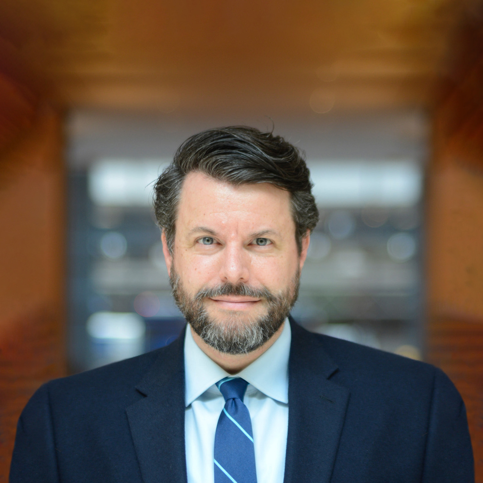 Portrait of author Charles Duhigg with a subtle smile and in a navy blue suit. 