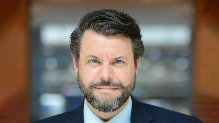 Portrait of author Charles Duhigg with a subtle smile and in a navy blue suit.